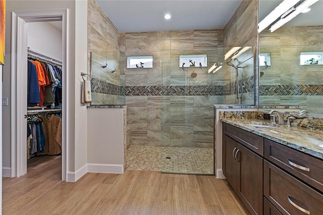 bathroom with hardwood / wood-style flooring, tiled shower, and vanity