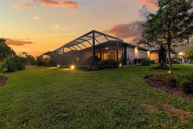 property exterior at dusk with a yard and glass enclosure