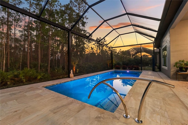 pool at dusk featuring a patio and glass enclosure