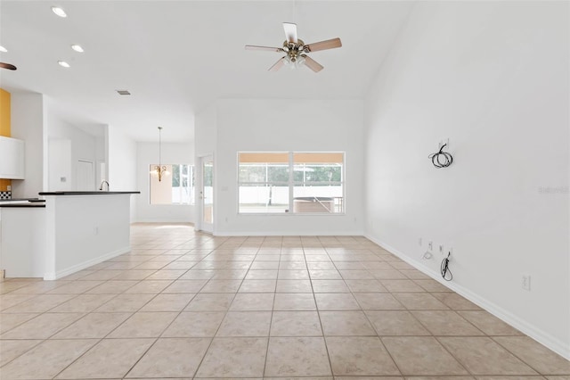 unfurnished living room with ceiling fan with notable chandelier and light tile patterned floors