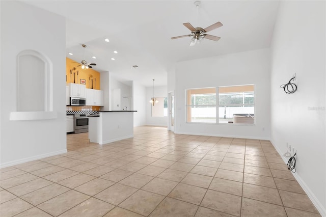 unfurnished living room featuring high vaulted ceiling, ceiling fan with notable chandelier, and light tile patterned floors