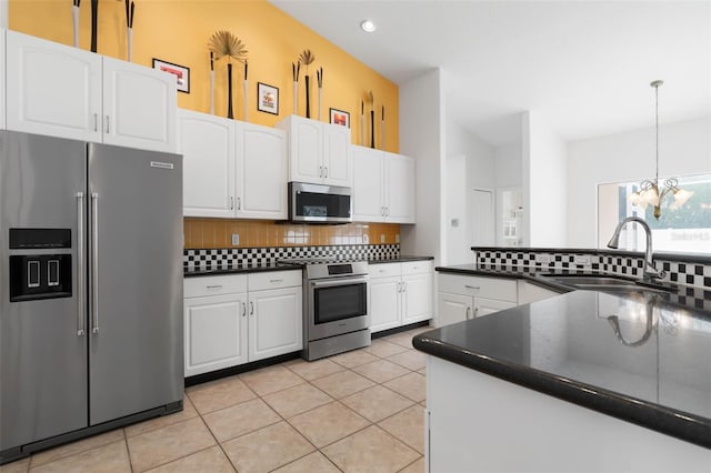 kitchen with sink, tasteful backsplash, light tile patterned floors, appliances with stainless steel finishes, and white cabinets