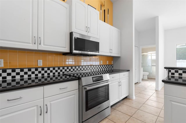 kitchen featuring tasteful backsplash, white cabinetry, appliances with stainless steel finishes, and light tile patterned floors