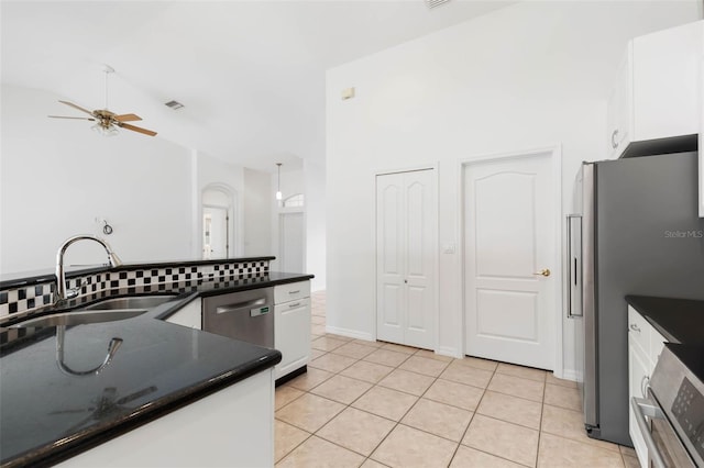 kitchen featuring vaulted ceiling, appliances with stainless steel finishes, sink, white cabinets, and light tile patterned floors