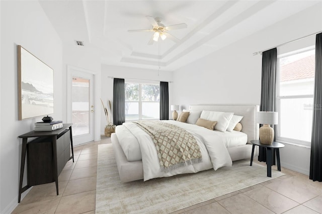 tiled bedroom featuring ceiling fan, a raised ceiling, and ensuite bath