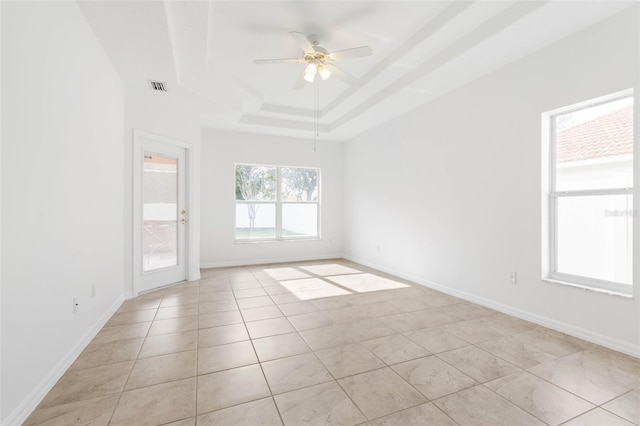 unfurnished room featuring light tile patterned floors, a tray ceiling, and ceiling fan