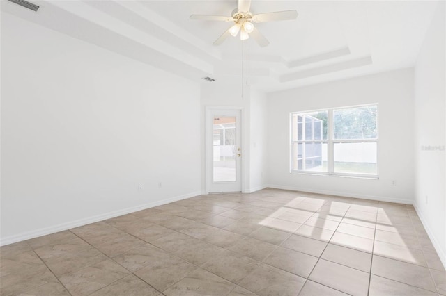 tiled spare room featuring ceiling fan and a tray ceiling