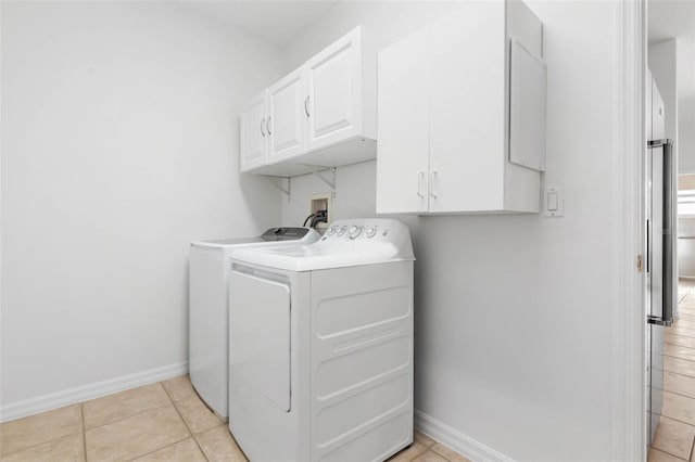 laundry area featuring light tile patterned floors, washing machine and dryer, and cabinets