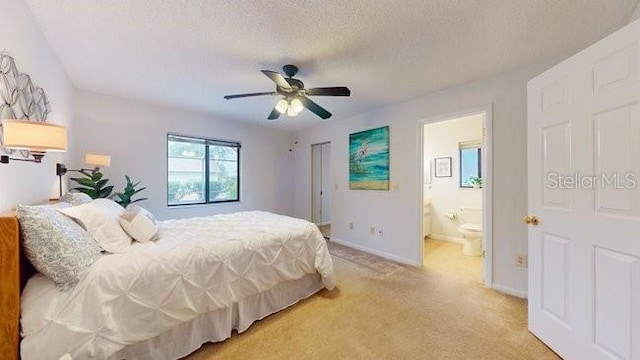 bedroom featuring light carpet, a textured ceiling, connected bathroom, and ceiling fan