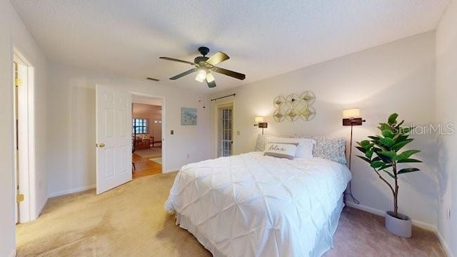 bedroom featuring ceiling fan, light colored carpet, and a textured ceiling