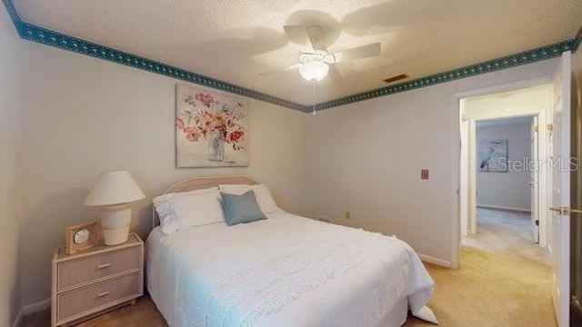 bedroom featuring ceiling fan, carpet flooring, and a textured ceiling