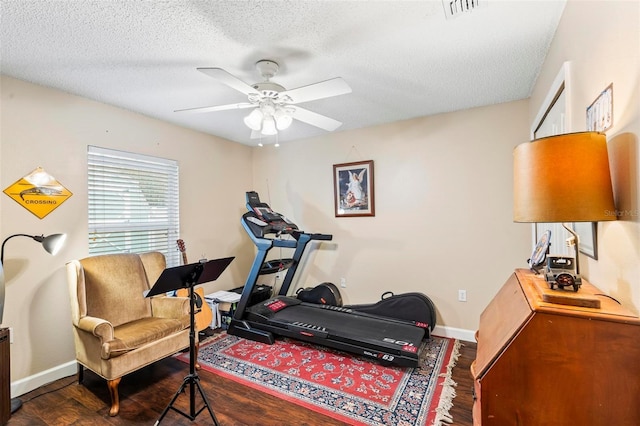 workout area with a textured ceiling, dark hardwood / wood-style floors, and ceiling fan