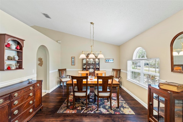 dining area featuring vaulted ceiling, dark wood-type flooring, and a textured ceiling