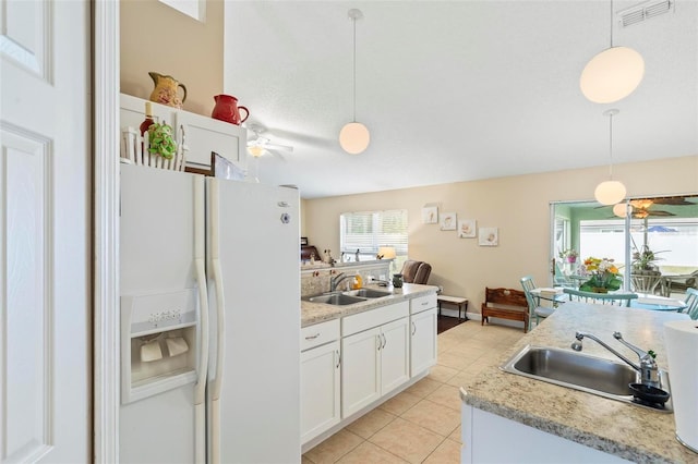 kitchen featuring pendant lighting, sink, white fridge with ice dispenser, and white cabinetry