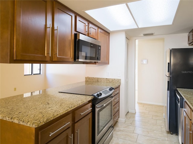 kitchen with light stone counters, stainless steel appliances, and light tile patterned floors