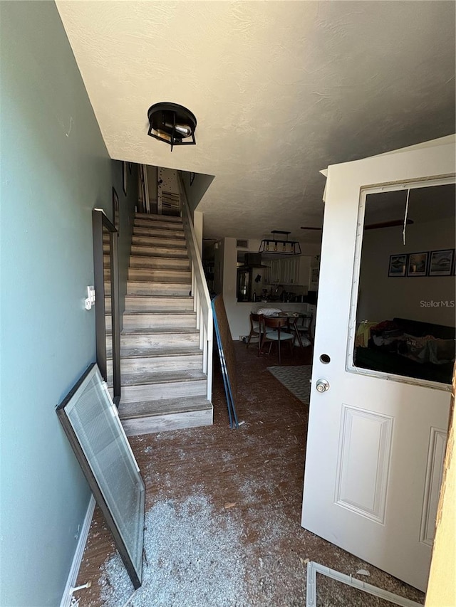 staircase featuring a textured ceiling