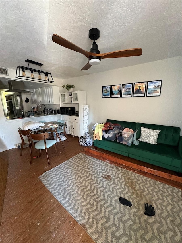 living room with ceiling fan, dark hardwood / wood-style floors, and a textured ceiling