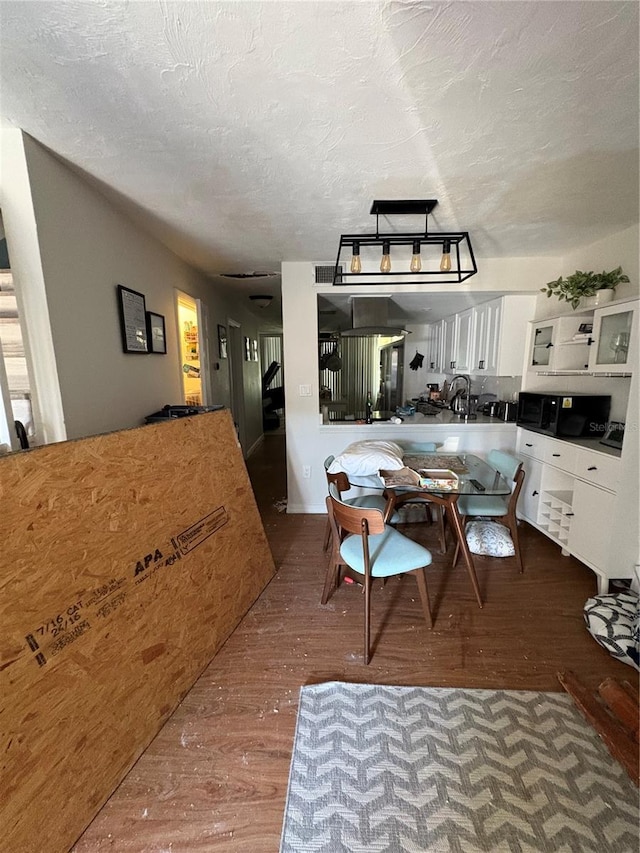 kitchen featuring hardwood / wood-style floors, a textured ceiling, sink, and white cabinets