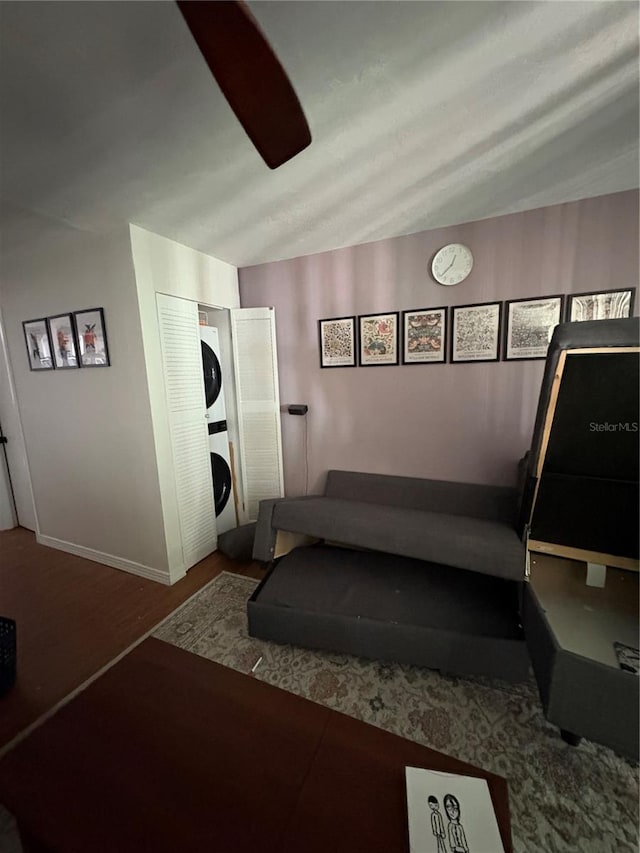 workout area with stacked washing maching and dryer, lofted ceiling, and wood-type flooring