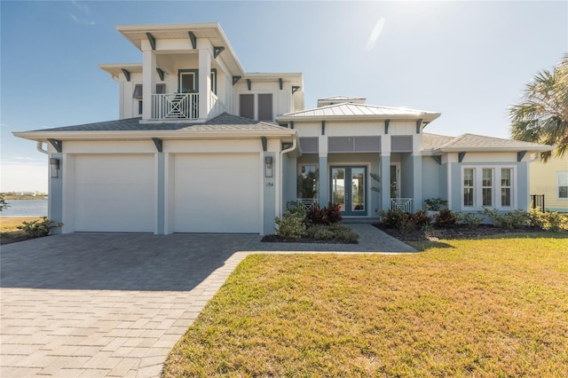 view of front of home with a garage, a balcony, a front lawn, and french doors