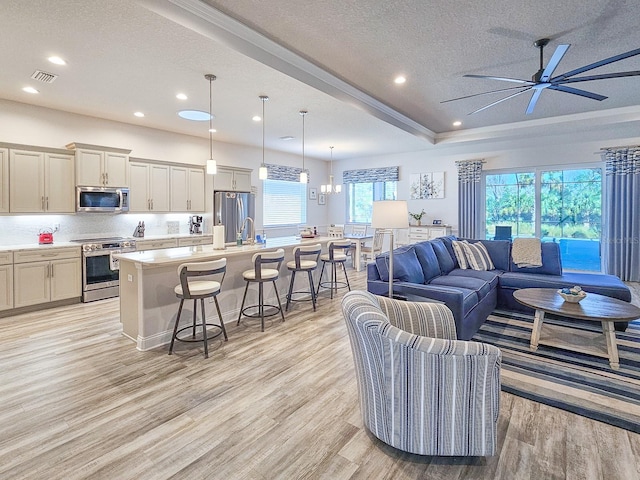 living room featuring ceiling fan, light hardwood / wood-style floors, sink, and a textured ceiling