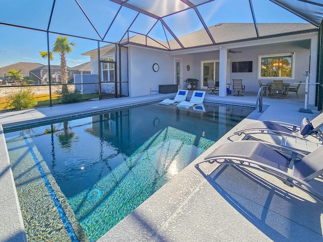 view of swimming pool with a patio, ceiling fan, and glass enclosure