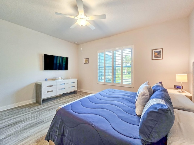 bedroom with a textured ceiling, light hardwood / wood-style flooring, and ceiling fan