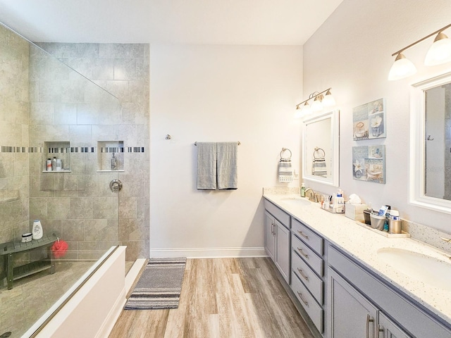 bathroom featuring hardwood / wood-style flooring, tiled shower, and vanity