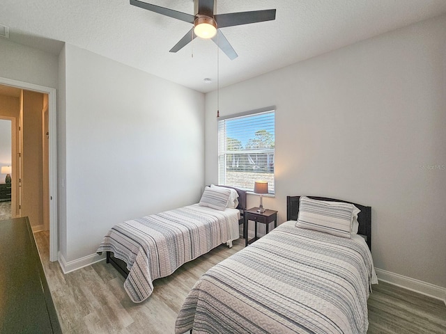 bedroom featuring ceiling fan, wood-type flooring, and a textured ceiling