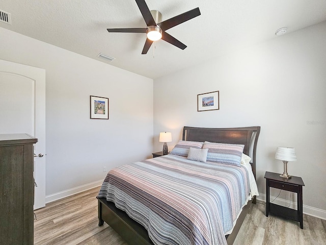 bedroom with a textured ceiling, ceiling fan, and light wood-type flooring