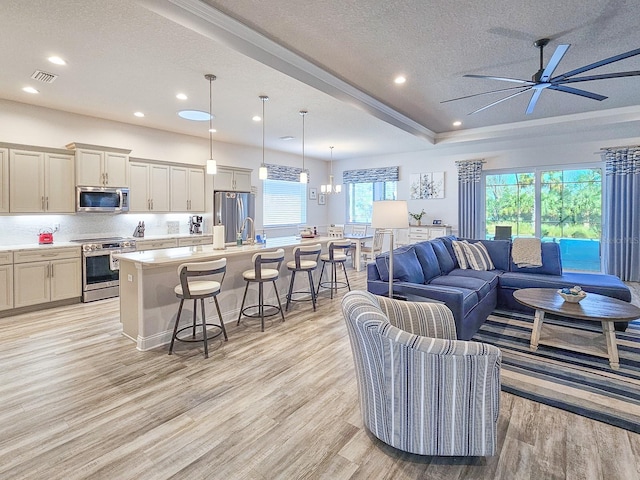 living room with ceiling fan, sink, a textured ceiling, and light wood-type flooring