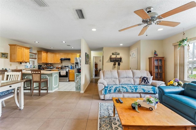 living room with light tile patterned floors, a textured ceiling, and ceiling fan