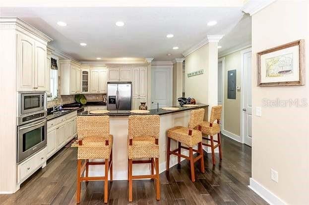 kitchen with stainless steel appliances, ornamental molding, dark hardwood / wood-style flooring, and a breakfast bar