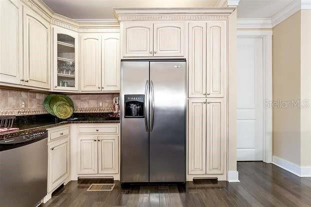 kitchen featuring backsplash, crown molding, dark hardwood / wood-style flooring, and stainless steel appliances