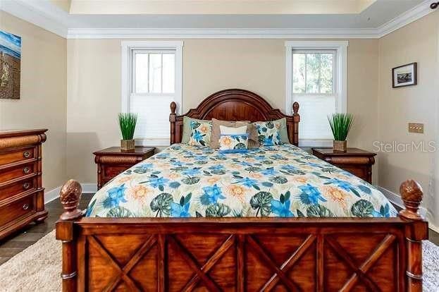 bedroom with hardwood / wood-style floors, a tray ceiling, and ornamental molding