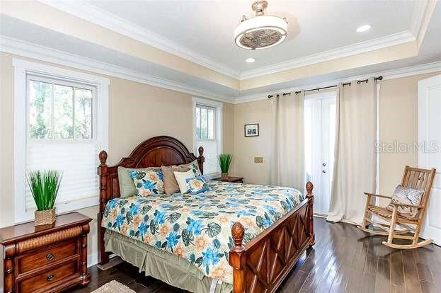 bedroom featuring crown molding, dark hardwood / wood-style floors, and a raised ceiling