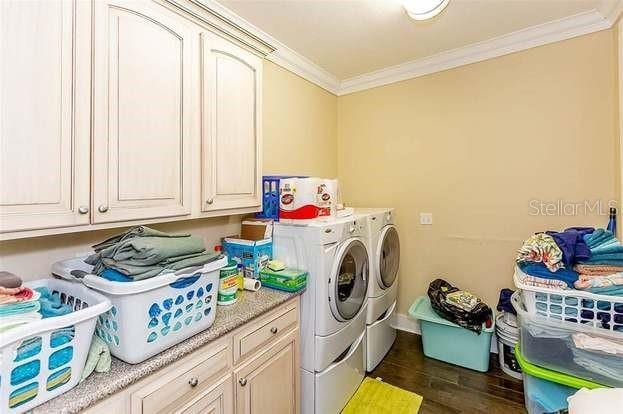 laundry area with cabinets, washer and clothes dryer, and ornamental molding