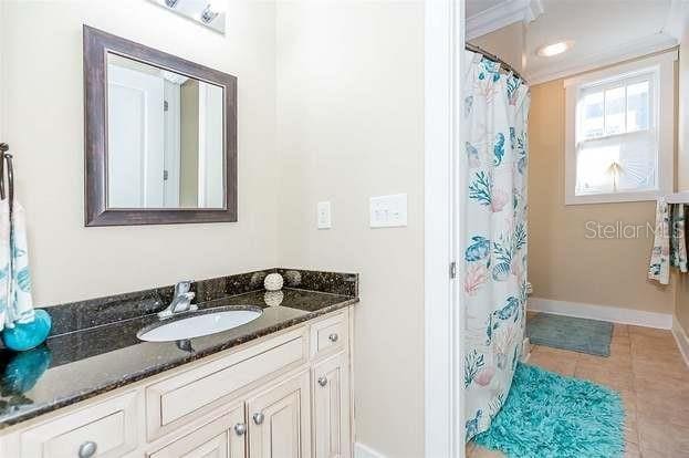 bathroom with a shower with curtain, vanity, tile patterned floors, and ornamental molding