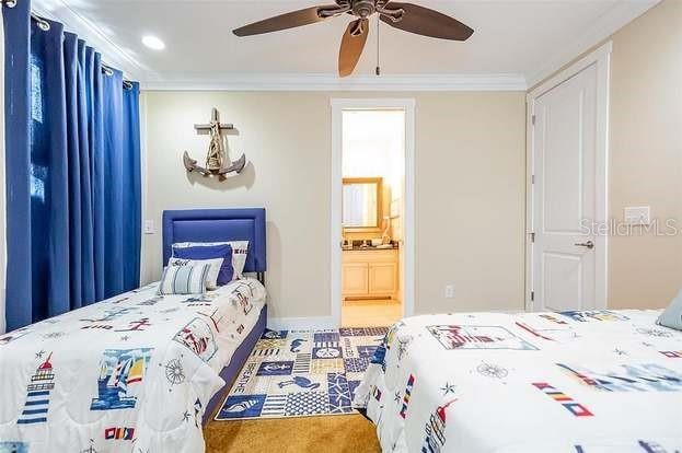 bedroom with ceiling fan, ensuite bathroom, and crown molding