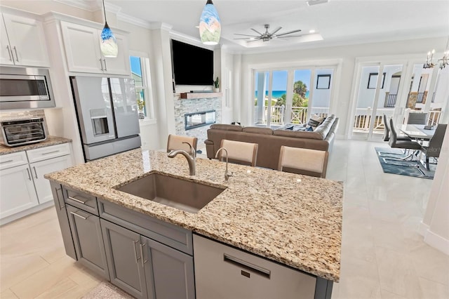 kitchen featuring appliances with stainless steel finishes, decorative light fixtures, white cabinetry, sink, and light stone counters