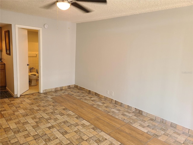 empty room with ceiling fan and a textured ceiling