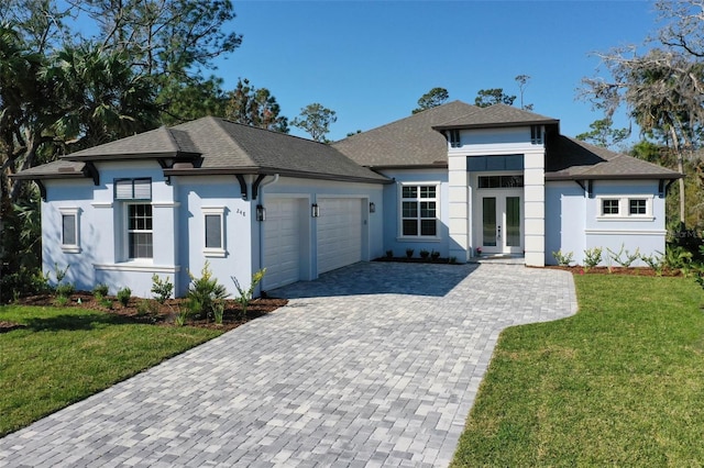 prairie-style house featuring a garage, decorative driveway, french doors, a front lawn, and stucco siding