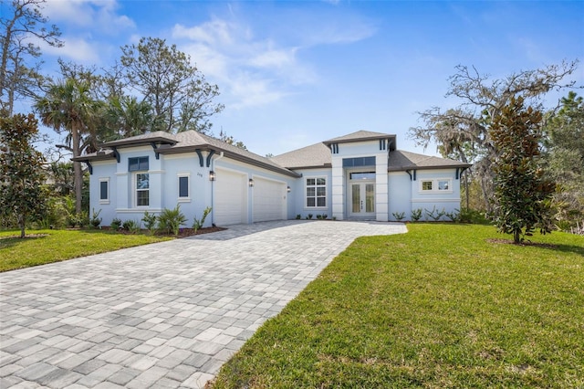 prairie-style home with decorative driveway, a front yard, french doors, and an attached garage