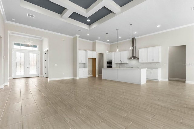 unfurnished living room with ornamental molding, french doors, a high ceiling, and baseboards