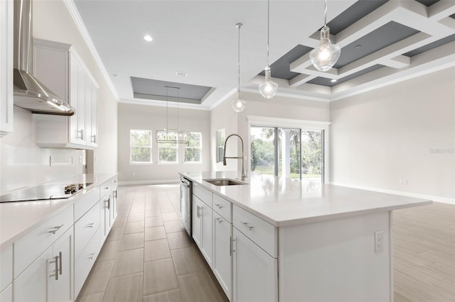 kitchen featuring light countertops, stainless steel dishwasher, ornamental molding, a sink, and wall chimney exhaust hood