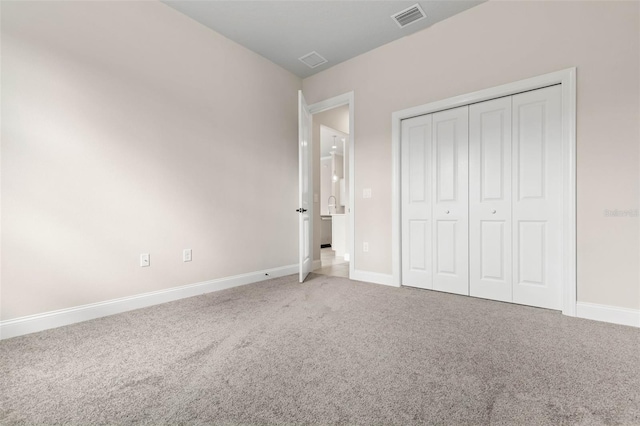 unfurnished bedroom with carpet floors, a closet, visible vents, and baseboards