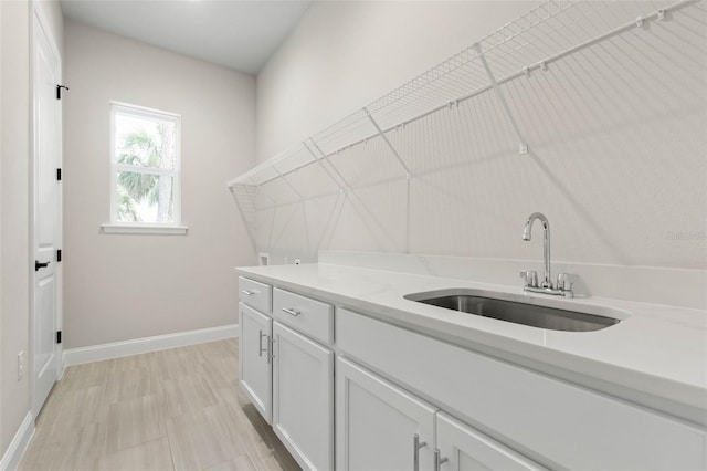 clothes washing area with baseboards and a sink