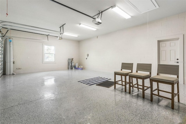 garage featuring a garage door opener and concrete block wall