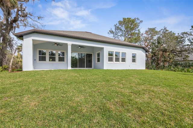 back of house featuring stucco siding, ceiling fan, and a yard