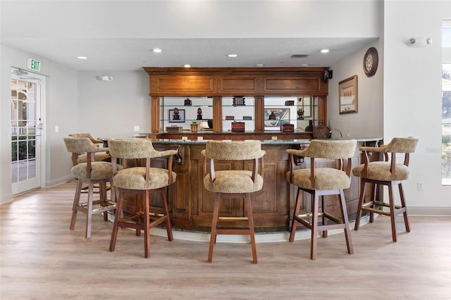 bar featuring light wood-style floors, indoor wet bar, and recessed lighting